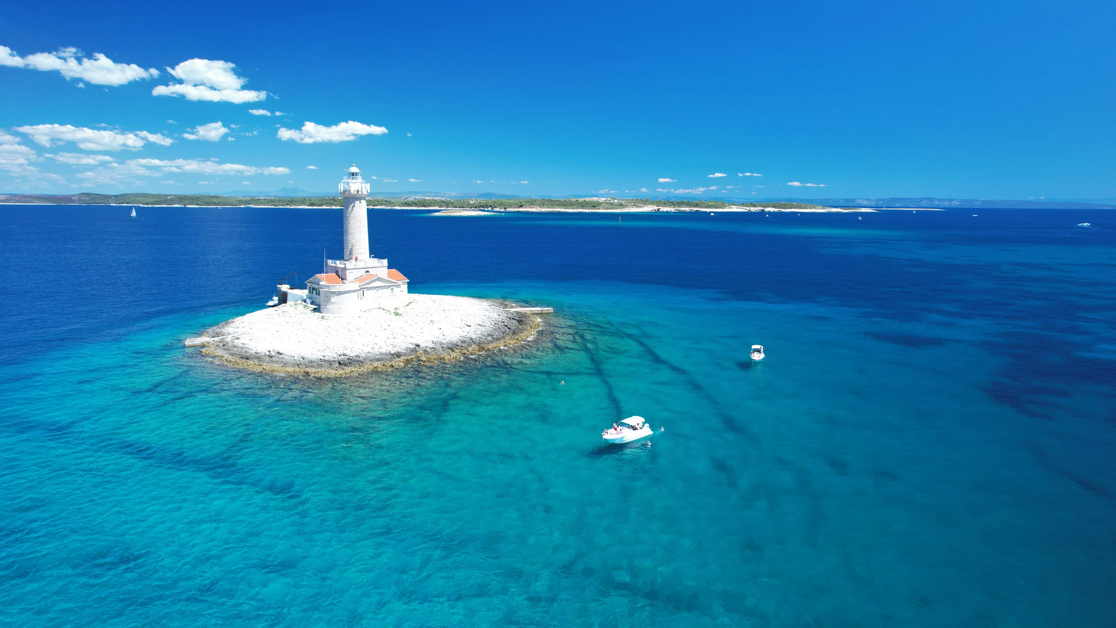 Stone lighthouse on a Croatian Adriatic cape with the lamp turning above the keeper's house.