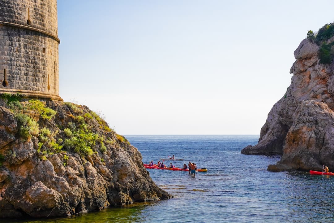 Sea kayakers paddling along the limestone cliffs beneath Dubrovnik's medieval city walls.