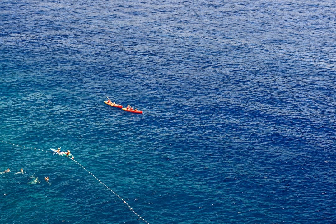 Solo kayaker shot from above on calm, deep-blue Adriatic water — the kind of conditions that experienced operators schedule for the early-morning window.
